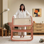A woman detaching the SnuzPod5 bassinet from the main rocking frame, showing how easily portable this baby cot is.