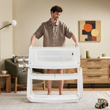 A man detaching the SnuzPod5 bassinet from the main rocking frame, showing how easily portable this baby cot is.

