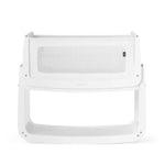 The SnuzPod5 bedside baby crib with a white wooden frame, white mesh sides, and a white mattress. 
