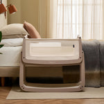 The SnuzPod 5 bedside baby crib with a lovely pale brown wooden frame, next to an adult's bed in a beautifully decorated bedroom.