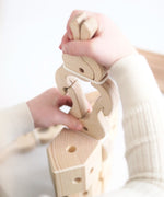 Child clamping a wooden Speelbelovend giant peg on another peg
