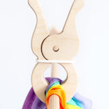 Speelbelovend giant wooden peg on wooden frame pole clamping the rainbow cotton cloth from Trigonos big start start