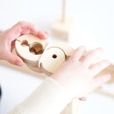 Child stacking wooden Speelbelovend giant play pegs on a Trigonos construction set