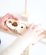 Child stacking wooden Speelbelovend giant play pegs on a Trigonos construction set