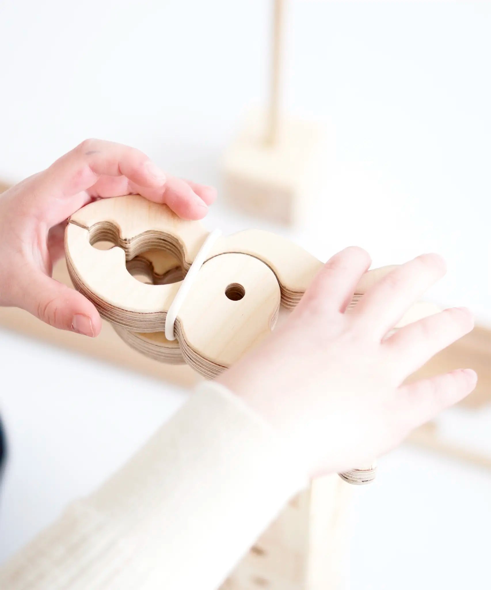 Child stacking wooden Speelbelovend giant play pegs on a Trigonos construction set
