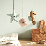 A closer look at the details on the Roommate Sealife Hanging Mobile. The blue starfish has sleepy eyes and dark blue spots. The Pink shell has sleepy eyes and white shell lines, and the sea horse is wide awake with light blue fins on its back