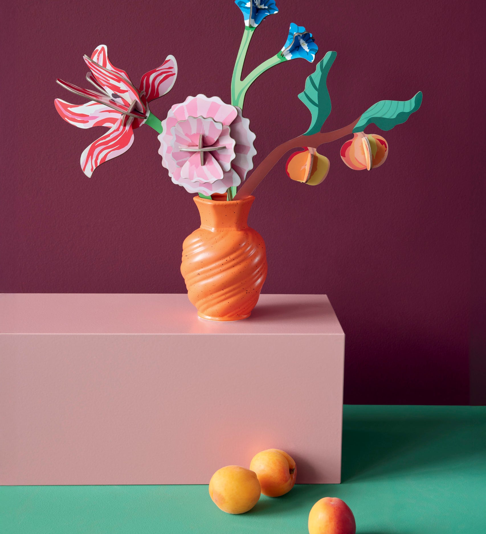 Studio roof small Dutch masters inspired bouquet decoration available at Babipur displayed in a orange vase standing on a pink platform