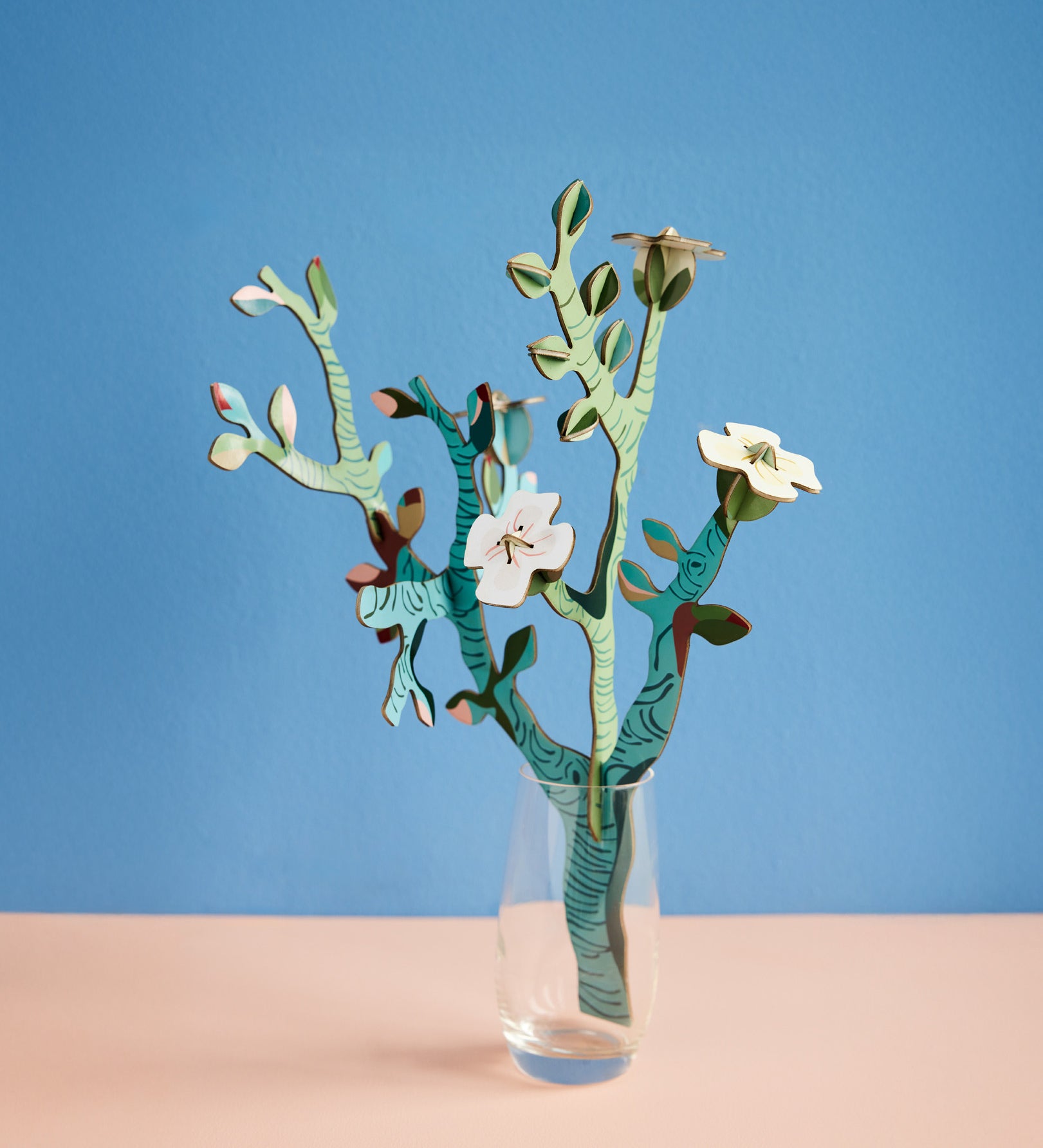 Studio roof small Van Gough inspired bouquet with almond blossom decoration available at Babipur displayed in a glass against a blue background.