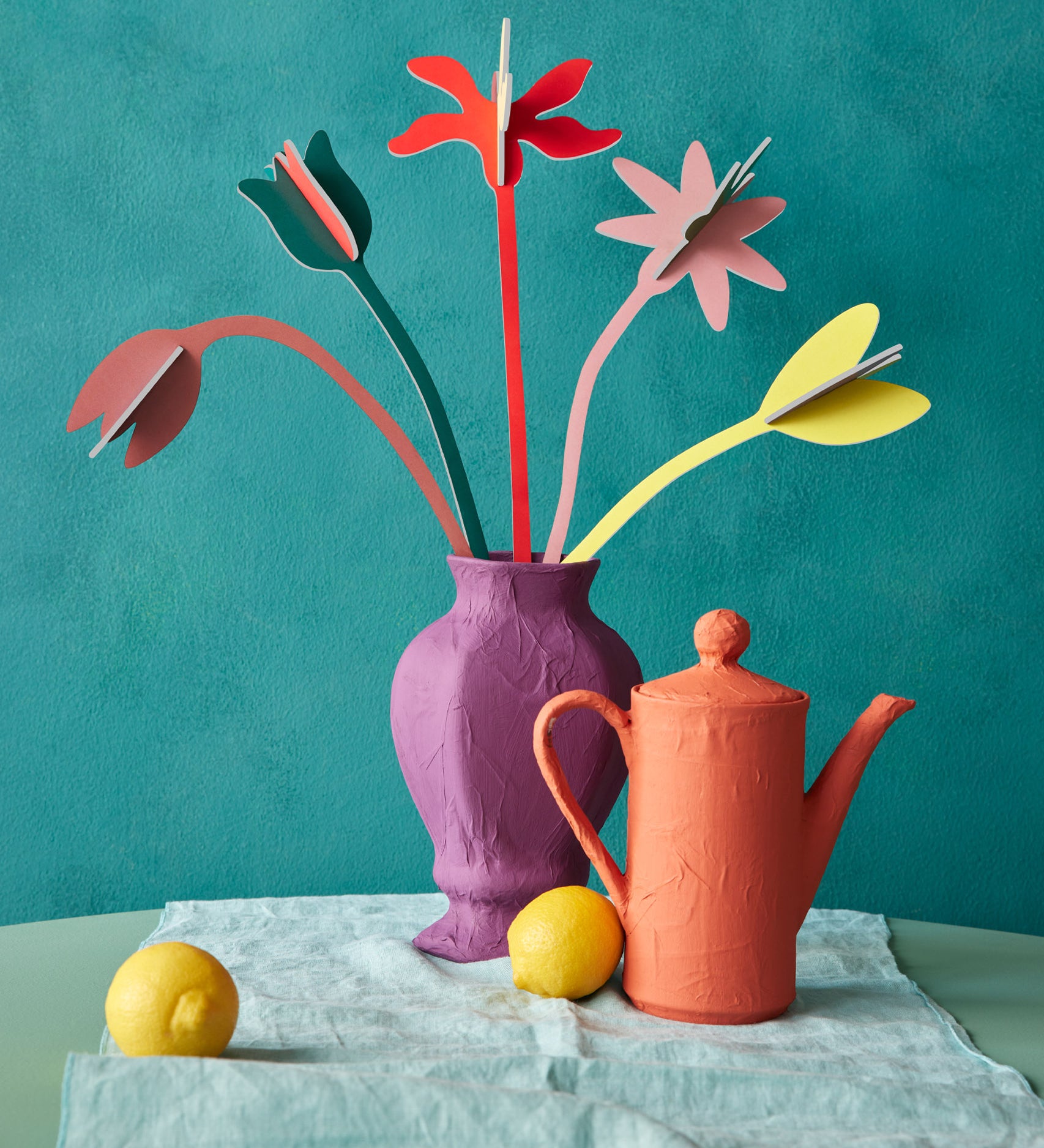 Studio Roof cardboard bouquet in blooming abundance colour way available at Babipur. A DIY kit made from cardboard displayed in a homemade paper mache vase next to a watering can 