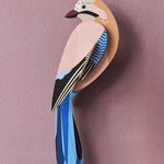 The Studio Roof Jay Cardboard Model, on a pink textured background