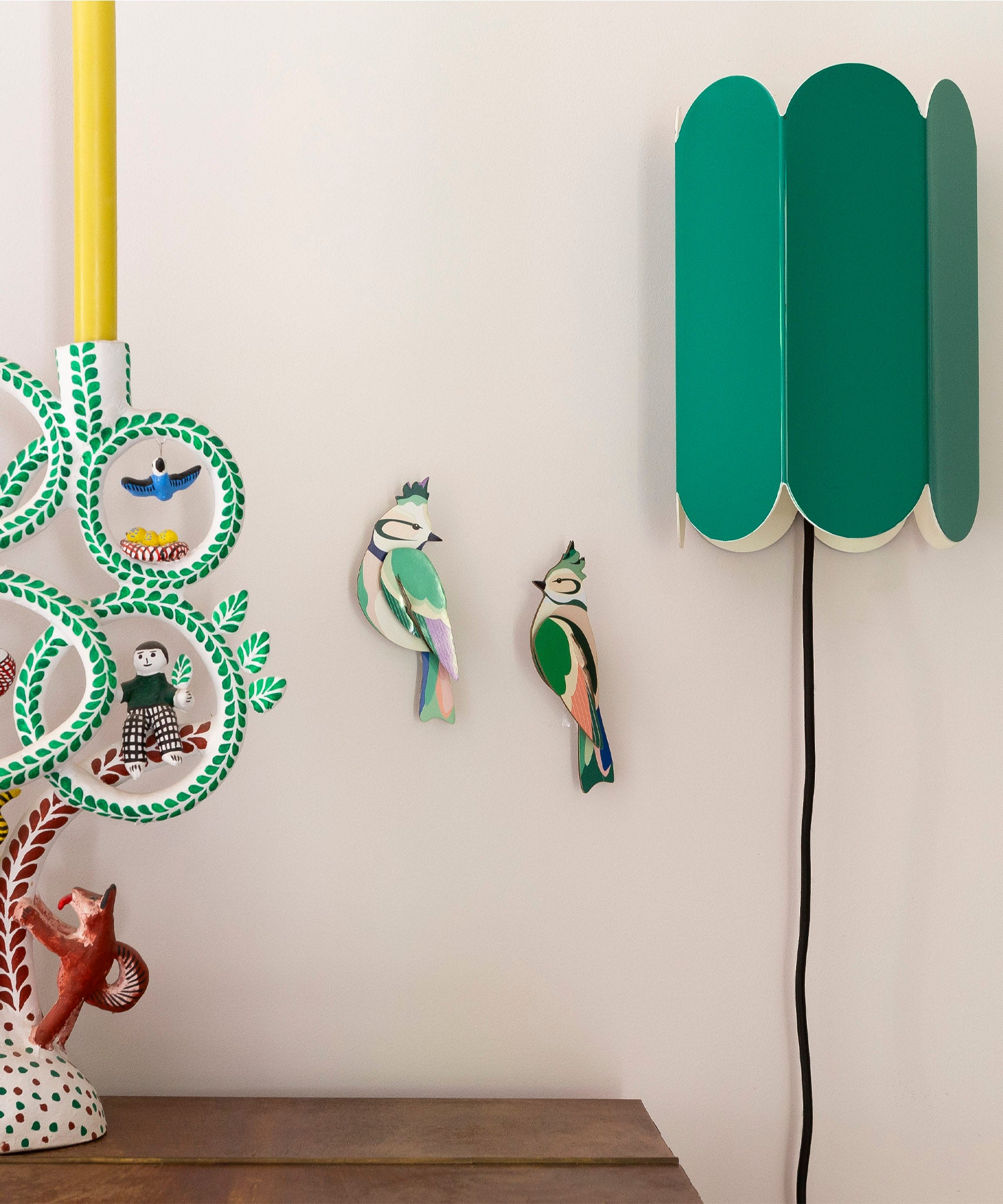 Studio Roof forest crests wall decorations available at Babipur. Hanging on a lightly coloured wall with a retro green lamp on the side