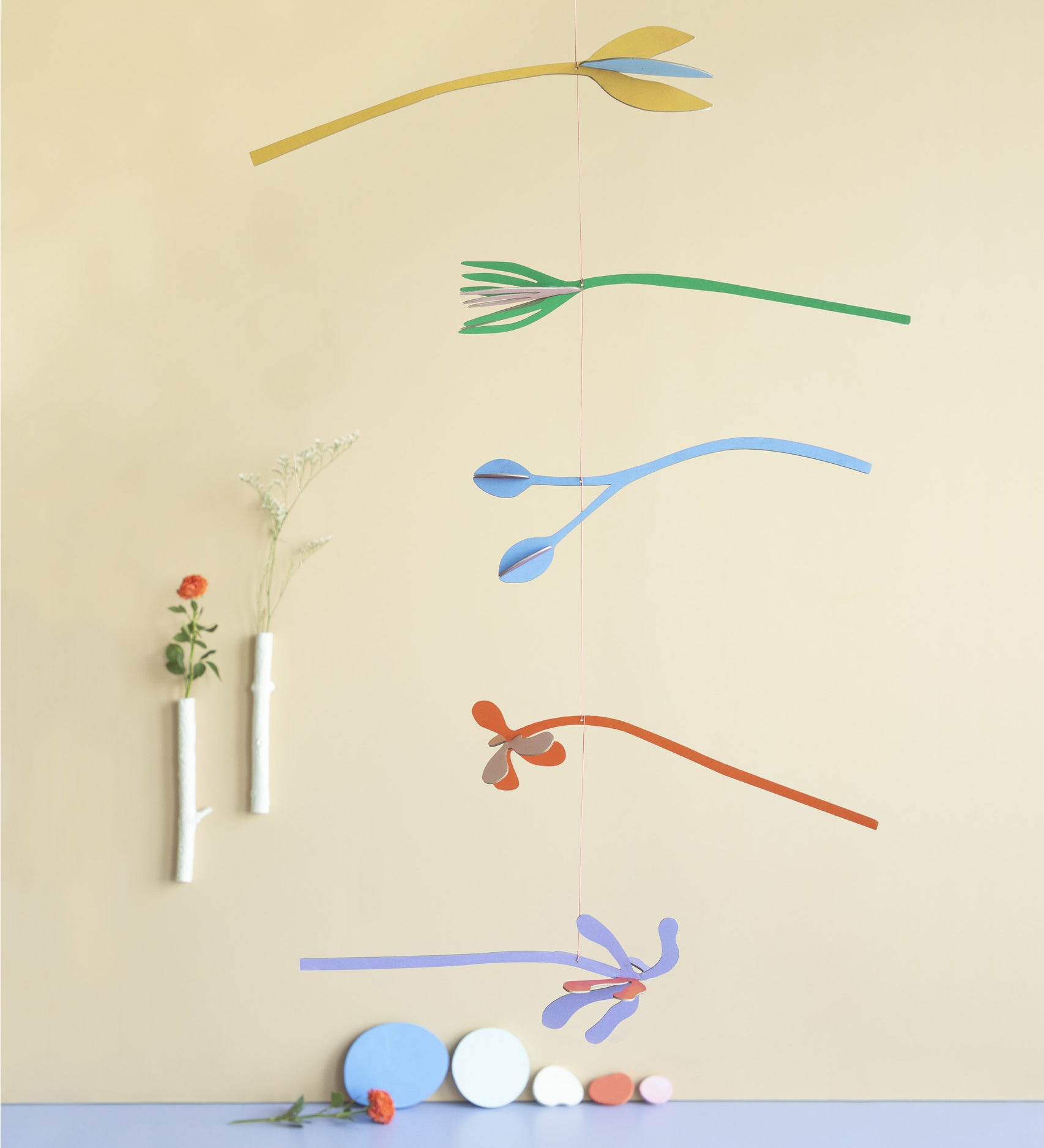 A Studio Roof cardboard Ophelia floral art mobile hanging over a table. This multicoloured floral DIY cardboard set is available at Babipur.