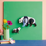 Studio Roof panda family wall decoration available at Babipur hanging on a green board against a lightly coloured wall