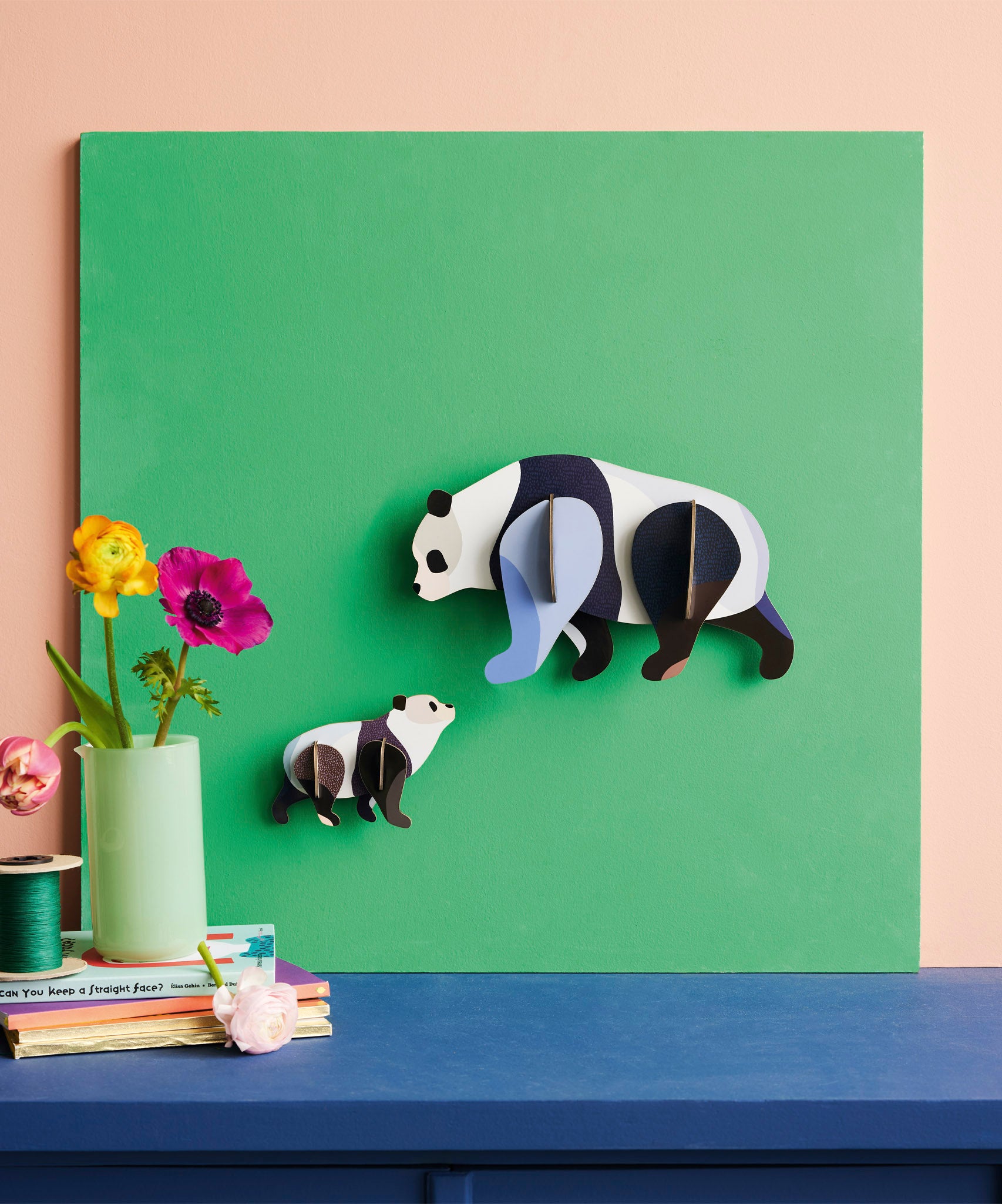 Studio Roof panda family wall decoration available at Babipur hanging on a green board against a lightly coloured wall