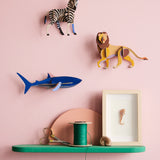 Studio Roof shark wall decoration available at Babipur hanging on a pink wall next to a lion and zebra DIY kit. 