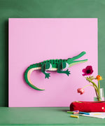 Studio Roof tall crcocdile wall decoration available at Babipur hanging on a pink board against a green wall 