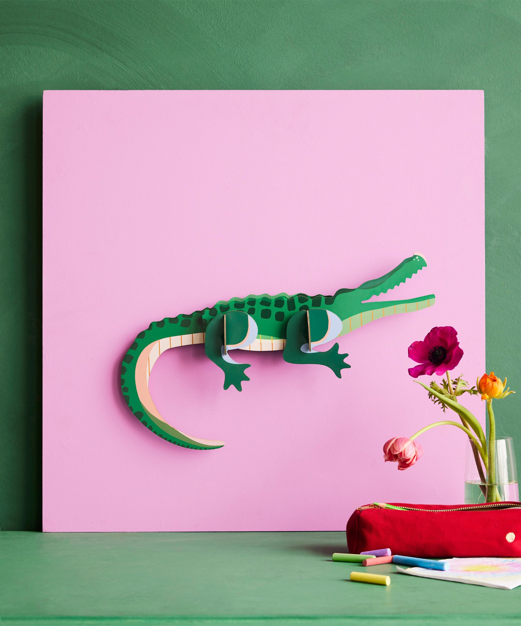 Studio Roof tall crcocdile wall decoration available at Babipur hanging on a pink board against a green wall 