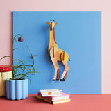 Studio Roof tall giraffe wall decoration available at Babipur hanging on a blue board above a desk