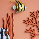 Studio Roof small angelfish wall decoration available at Babipur hanging on a lightly coloured wall next to a striped vase