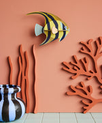 Studio Roof small angelfish wall decoration available at Babipur hanging on a lightly coloured wall next to a striped vase