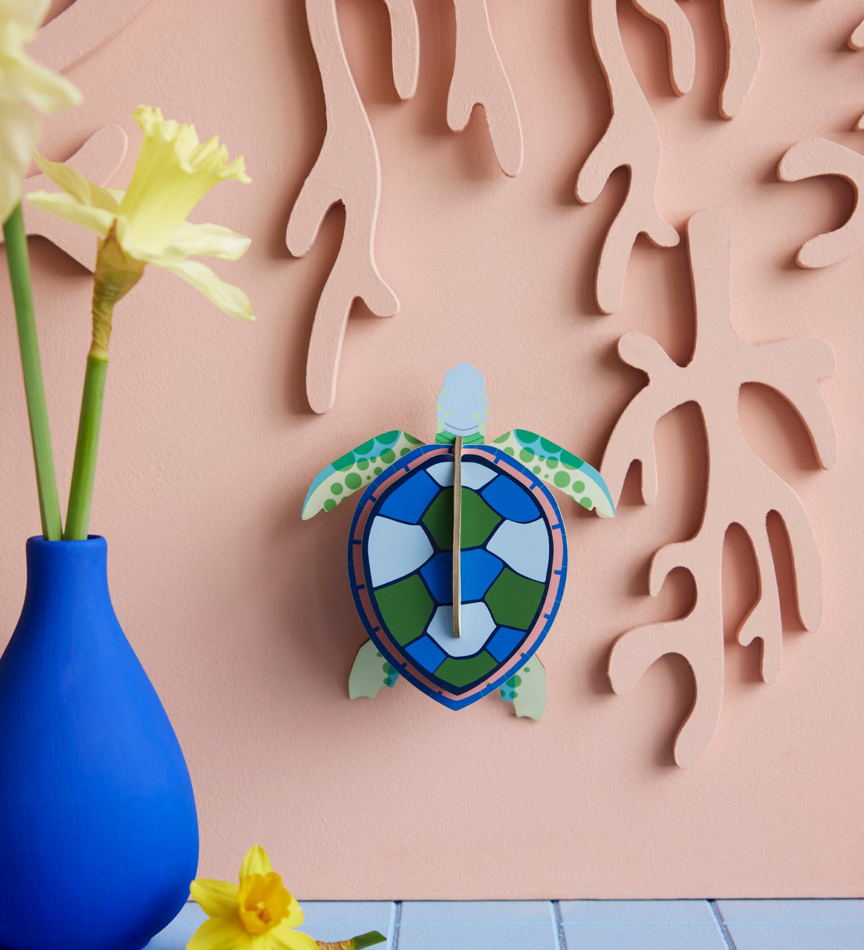 Studio Roof small turtle wall decoration available at Babipur hanging lightly coloured wall next to a blue vase