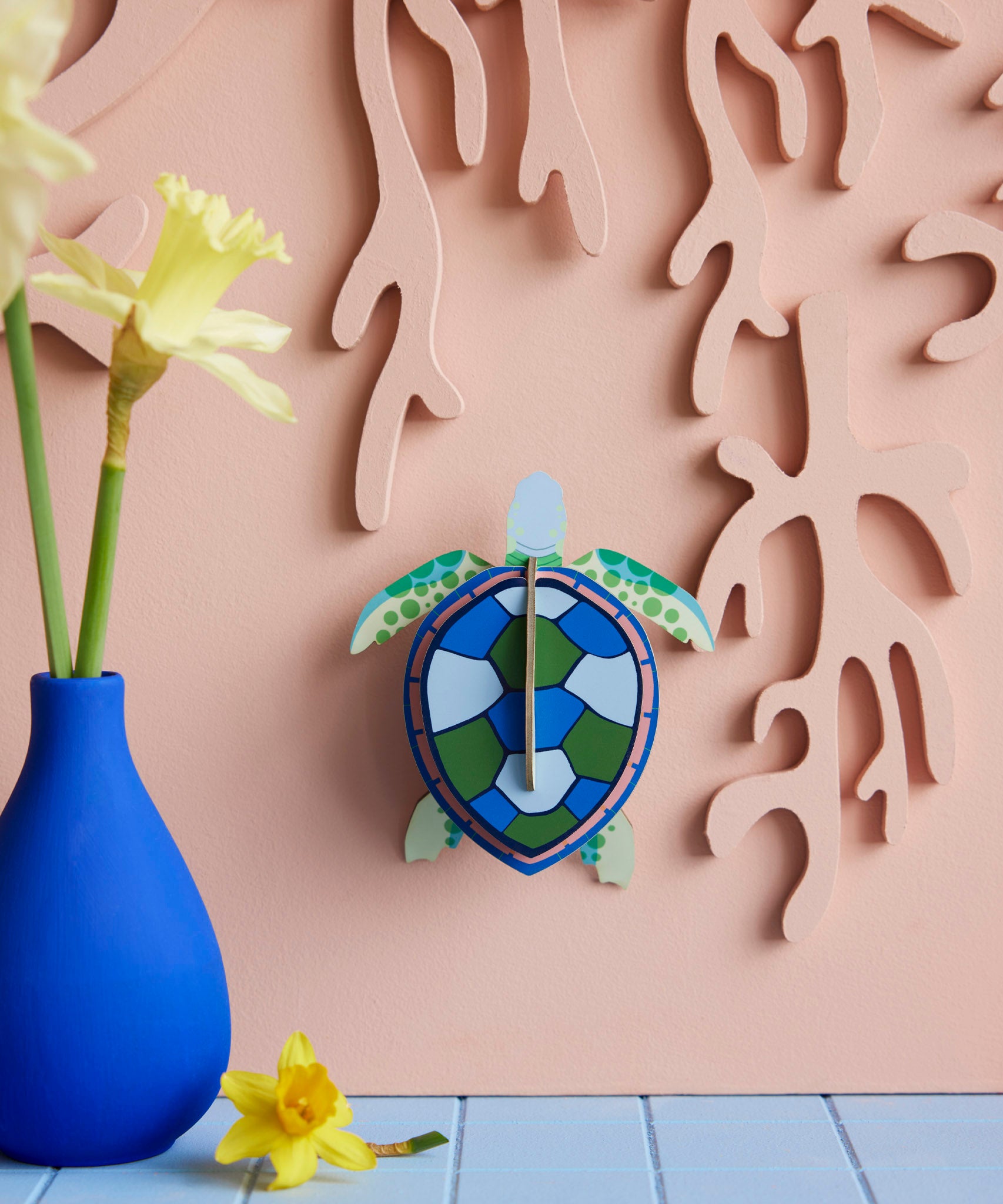Studio Roof small turtle wall decoration available at Babipur hanging lightly coloured wall next to a blue vase