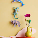 Studio Roof dolphin wall decoration available at Babipur hanging on a yellow wall next to a gecko and elephant DIY hanging decoration