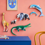 Studio Roof tall giraffe wall decoration available at Babipur hanging on a pink wall next to a panda, crocodile and dolphin DIY kits