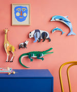 Studio Roof tall giraffe wall decoration available at Babipur hanging on a pink wall next to a panda, crocodile and dolphin DIY kits