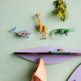 Studio Roof whale wall decoration available at Babipur hanging on a green wall next to a giraffe and crocodile DIY kit. 