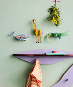 Studio Roof whale wall decoration available at Babipur hanging on a green wall next to a giraffe and crocodile DIY kit. 