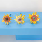 The Studio Roof Cardboard Bouquet - Van Gogh Sunflowers laid down on a blue table with the flower heads being the main focus point of the picture