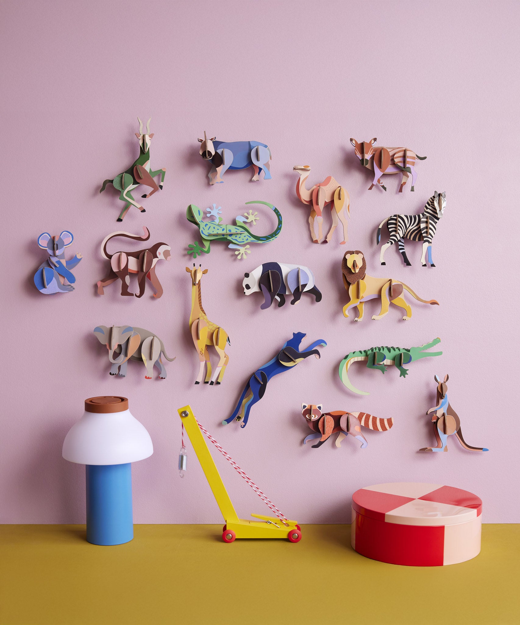 The Studio Roof Wildlife Animals 3D Cardboard Models collection all displayed on a pink background - 16 in total. They are displayed with a collection of decorative items on a table.