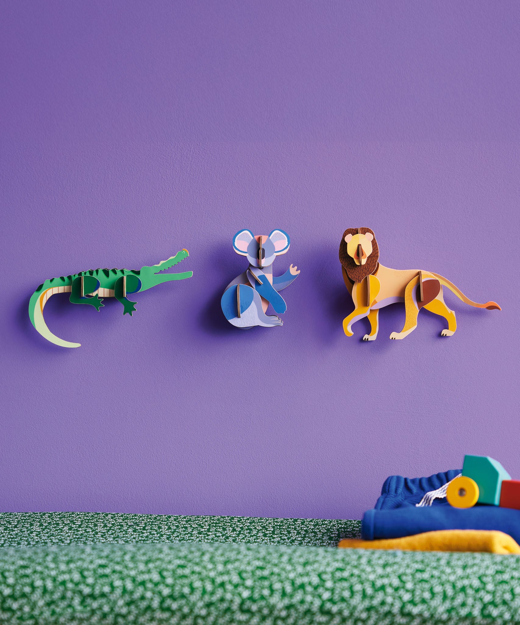 3 Studio Roof 3D Cardboard Models of Wildlife Animals on a purple wall - the Crocodile, Koala and the Lion. They are pictured with decorative objects.