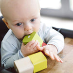 A baby teething on a block from the Tegu Baby's First Magnetic Blocks - 15 Piece
