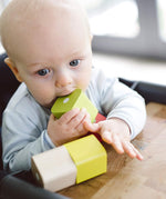 A baby teething on a block from the Tegu Baby's First Magnetic Blocks - 15 Piece