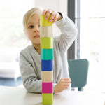 A child stacking the Tegu Magnetic Blocks on top of each other whilst sat at a white table