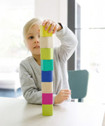 A child stacking the Tegu Magnetic Blocks on top of each other whilst sat at a white table