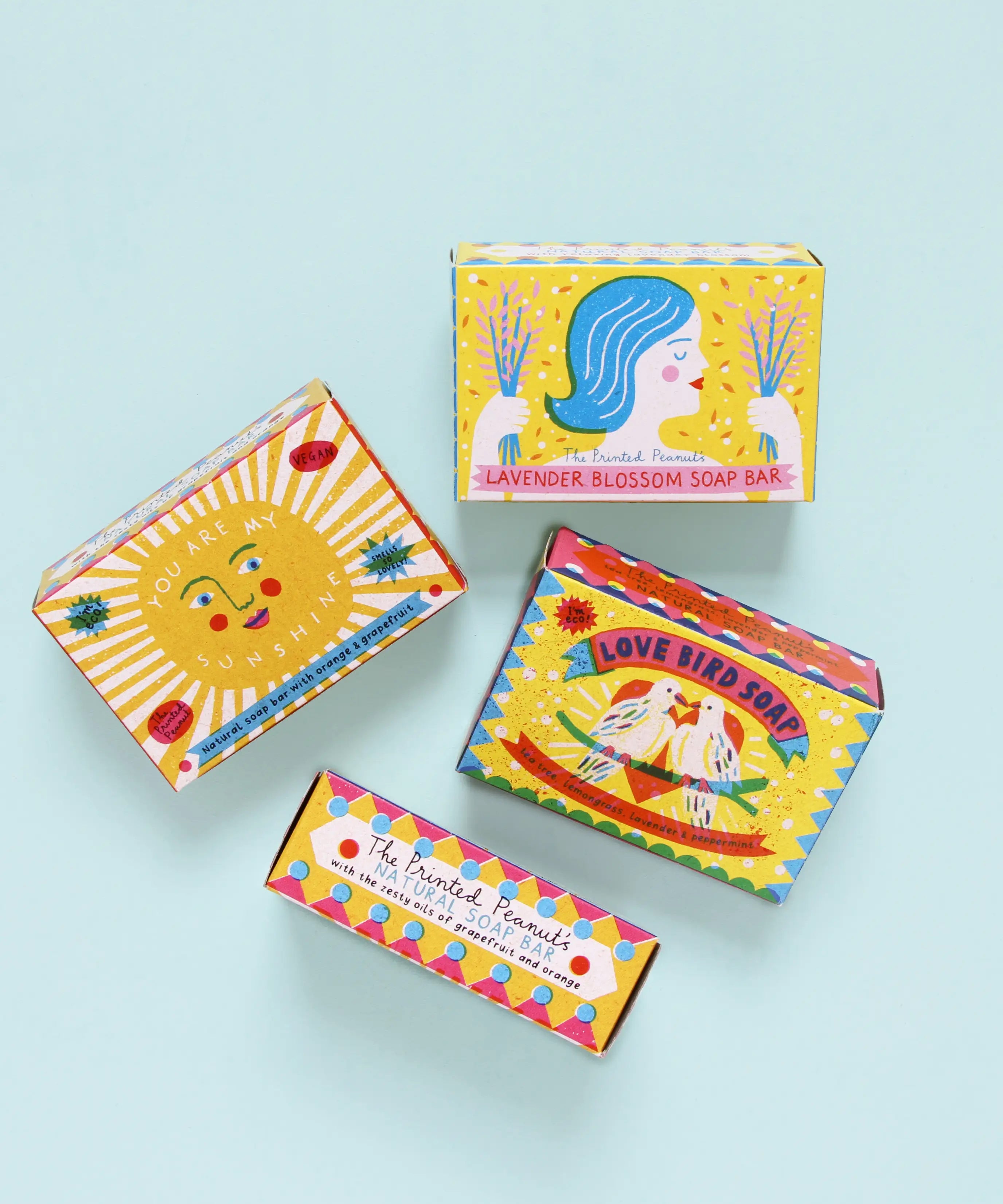 A group of The Printed Peanut sunshine natural handmade soaps showing their decorated packaging box against a blue background.