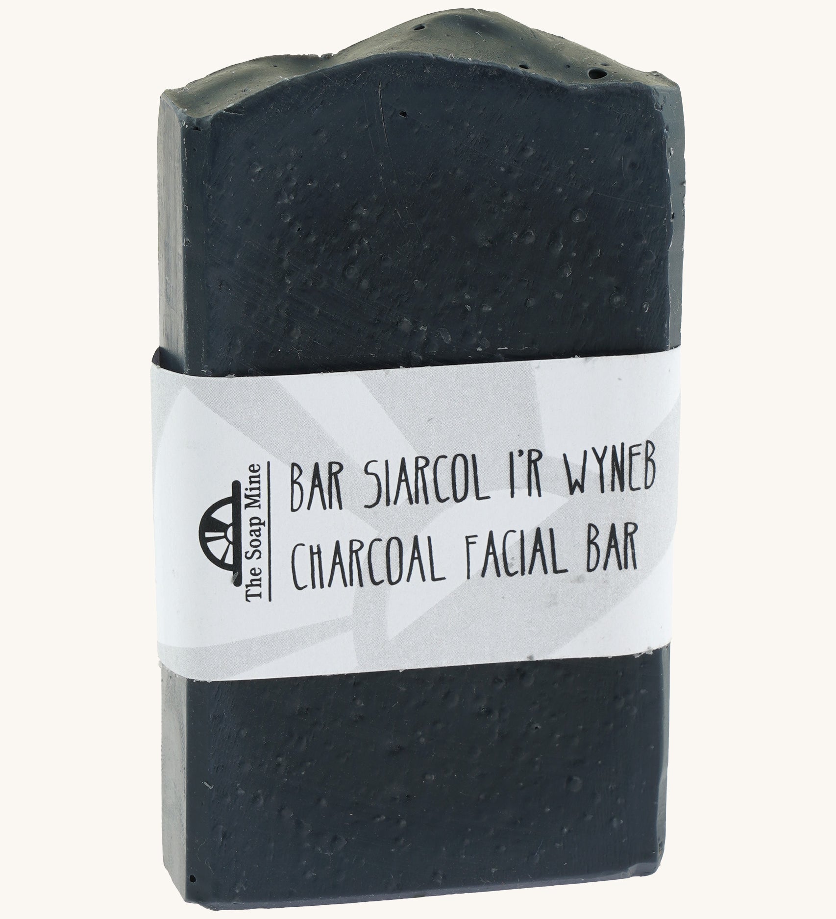 The Soap Mine Charcoal facial bar available at Babipur. A deep slate grey coloured soap bar with a cardboard branding strip.
