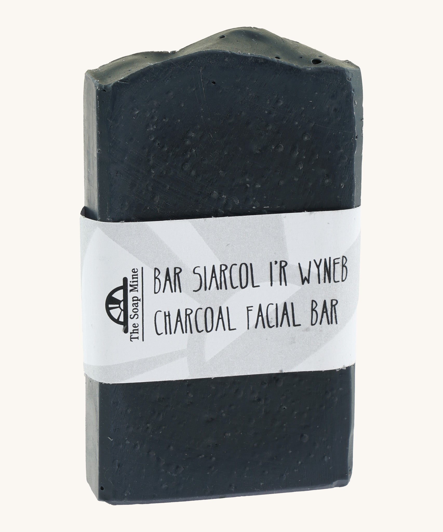 The Soap Mine Charcoal facial bar available at Babipur. A deep slate grey coloured soap bar with a cardboard branding strip.
