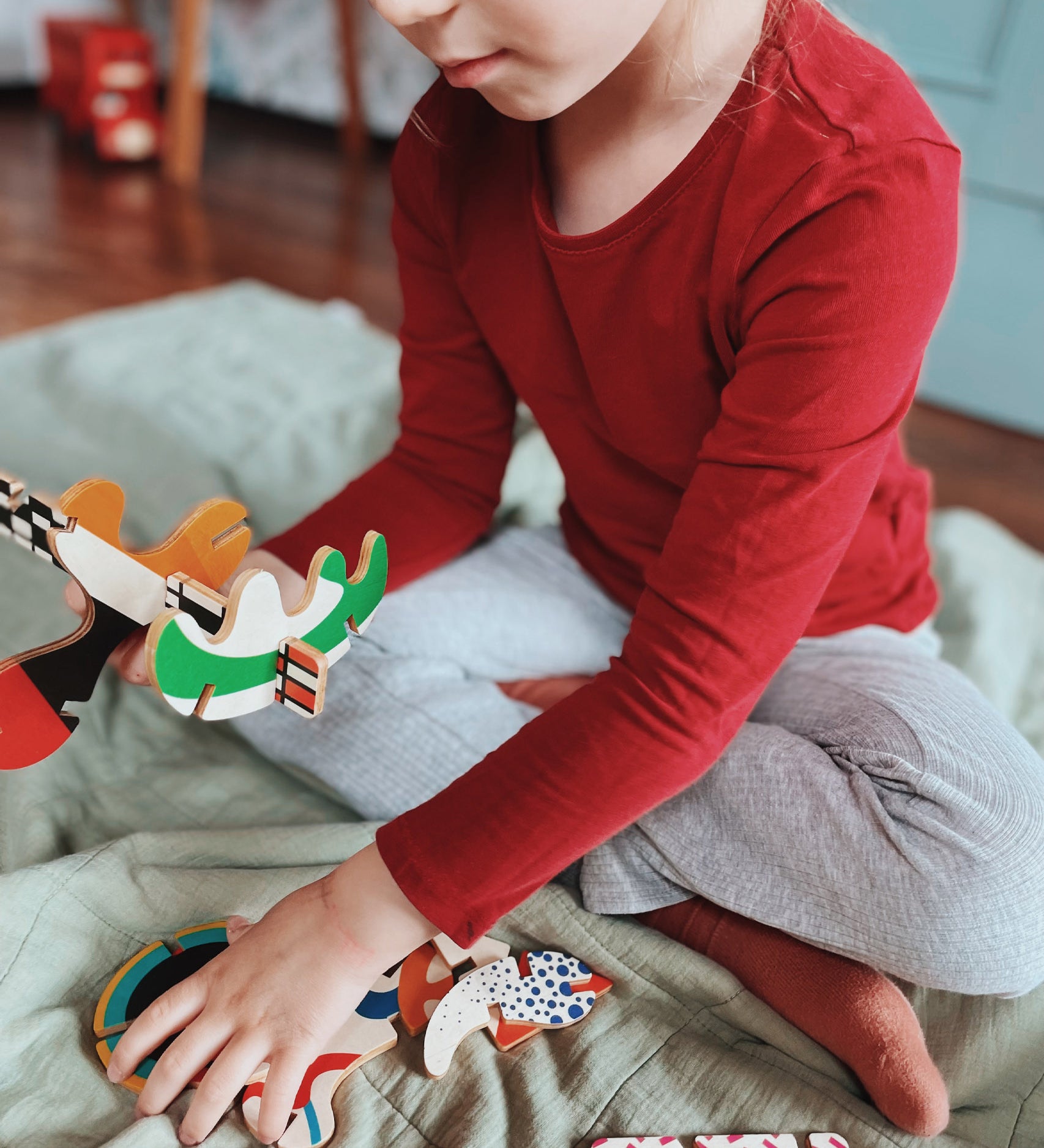 A close up of a child holding some of the piece from the Bajo abstract art puzzle set available at Babipur showing scale 