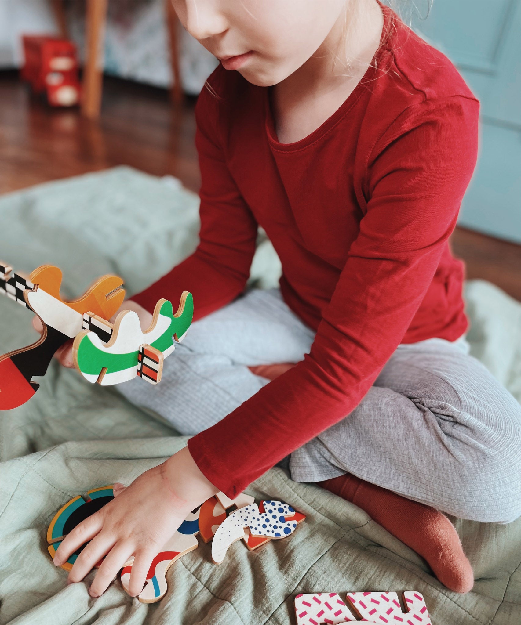 A close up of a child holding some of the piece from the Bajo abstract art puzzle set available at Babipur showing scale 
