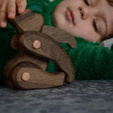 A close up of a child playing with the Tobe wooden toy gorilla figure available at Babipur showing the joint detail on the limbs 