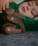 A close up of a child playing with the Tobe wooden toy gorilla figure available at Babipur showing the joint detail on the limbs 
