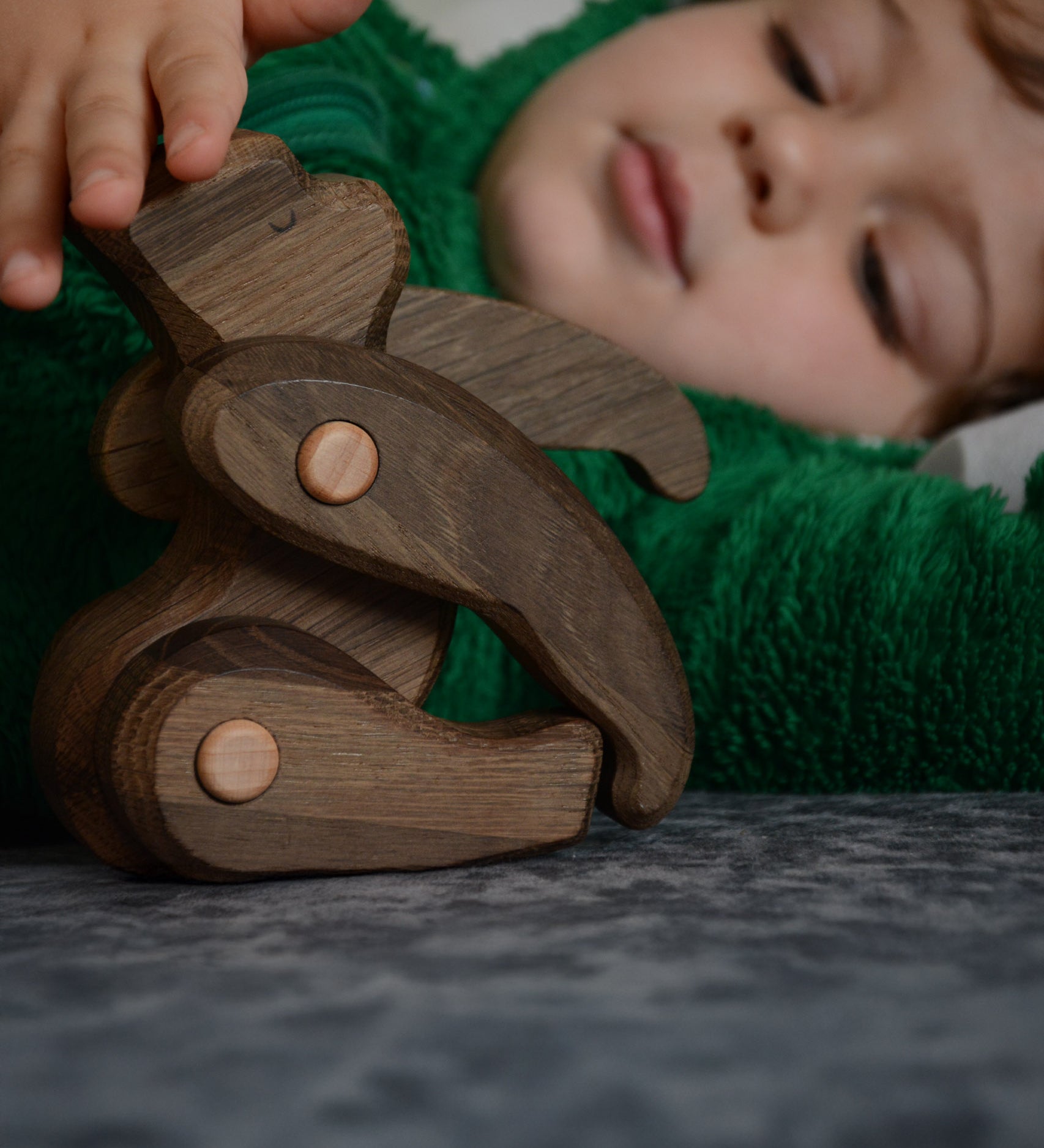 A close up of a child playing with the Tobe wooden toy gorilla figure available at Babipur showing the joint detail on the limbs 