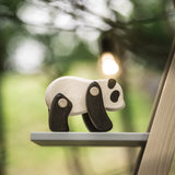 A Tobe Wooden Panda toy available at Babipur. This panda is displayed outdoors on a shelf and showing the movable joints