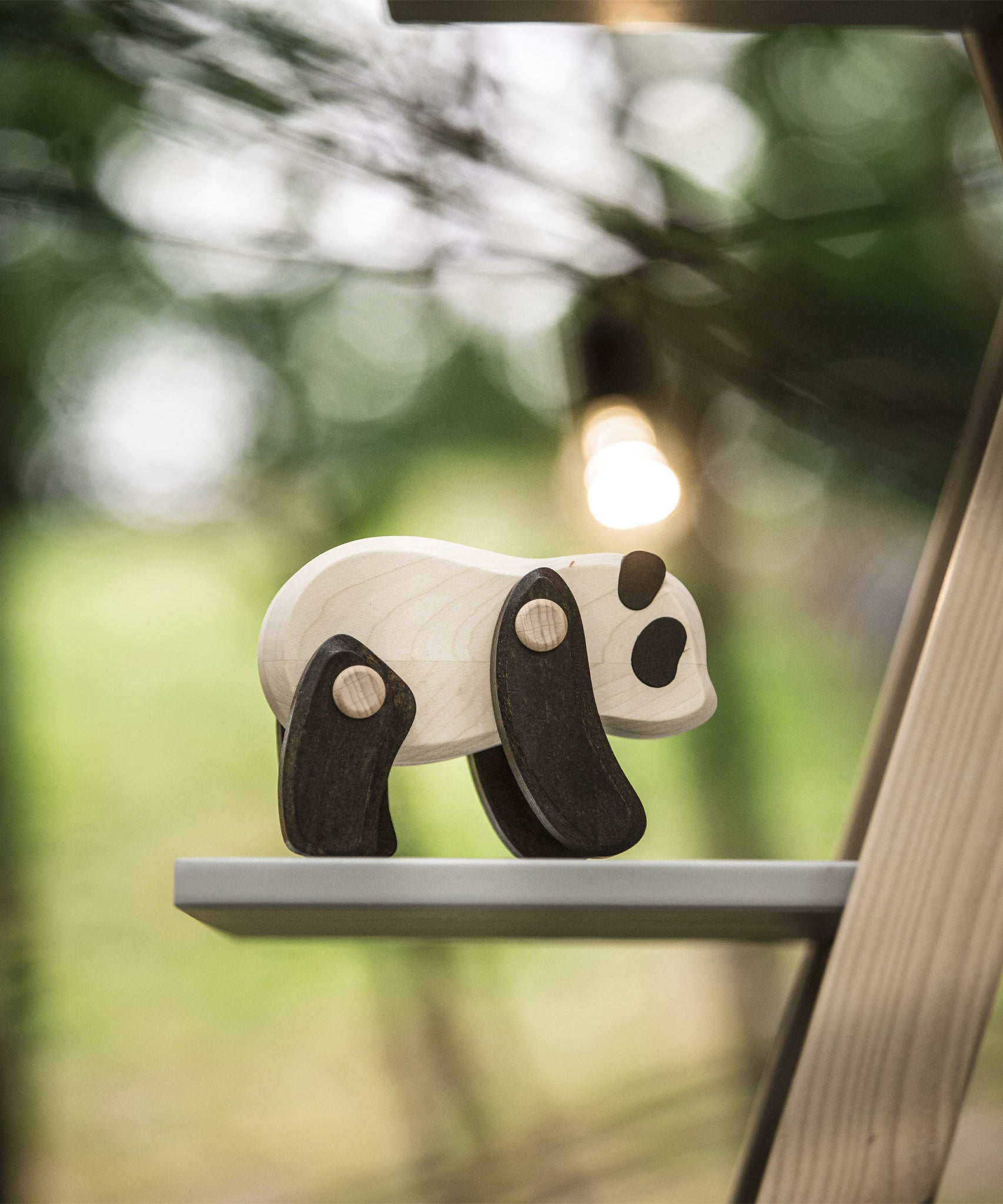 A Tobe Wooden Panda toy available at Babipur. This panda is displayed outdoors on a shelf and showing the movable joints