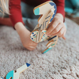 A close up of a child assembling some of pieces from the Tobe Pegasus Fantasy Animals wooden Puzzle that's available at Babipur showing the plywood cut detail 