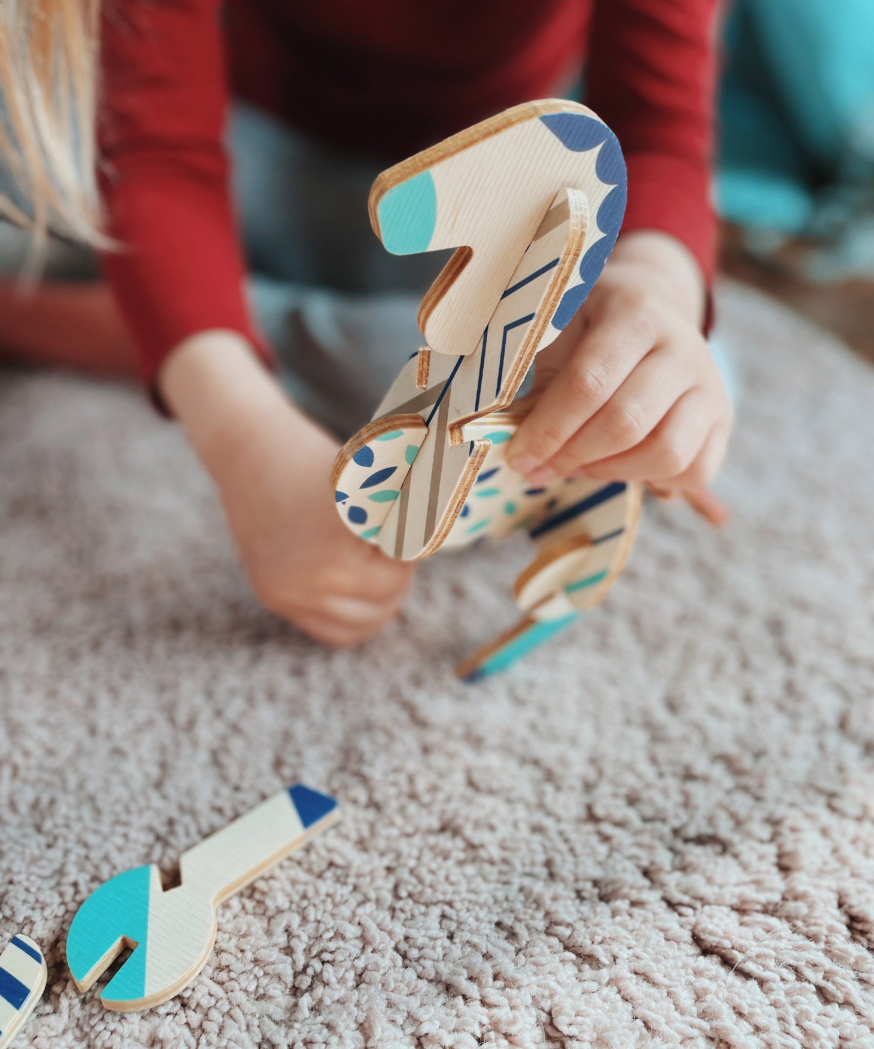 A close up of a child assembling some of pieces from the Tobe Pegasus Fantasy Animals wooden Puzzle that's available at Babipur showing the plywood cut detail 